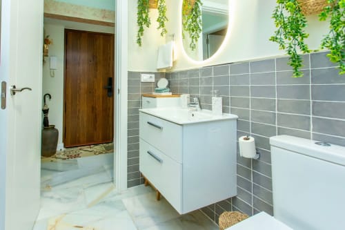 Modern bathroom at G&H Apartments in Jerez de la Frontera with white vanity, gray tile walls, and green plants