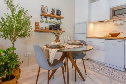 Modern kitchen dining area at G&H Apartments in Jerez de la Frontera with round table, white cabinetry, and potted plants