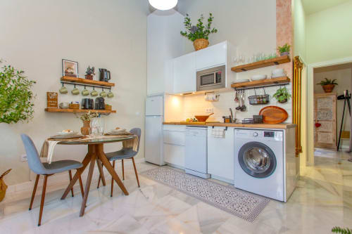 Modern kitchen and dining area in Le Petit Palace apartment, Jerez de la Frontera with white appliances and wooden shelving