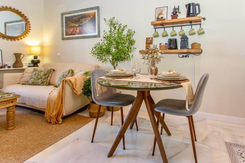 Modern studio apartment in Jerez with round dining table, comfortable sofa, wooden shelves, and kitchen amenities