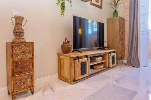 Modern apartment living room at G&H Apartments in Jerez with wooden TV stand, flat-screen TV, and carved wooden storage