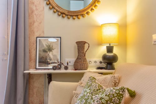 Cozy bedroom corner at G&H Apartments Jerez with lamp, mirror, desk décor, and city view