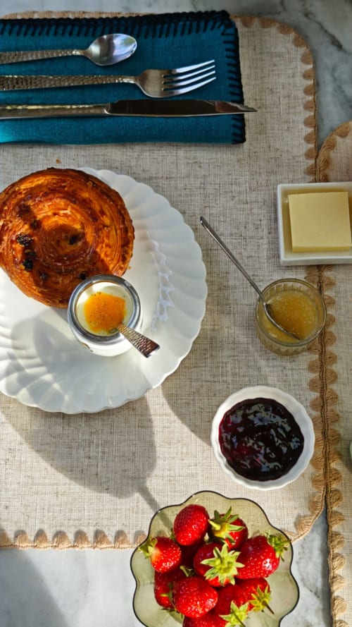 Petit-déjeuner raffiné à La Maison 1903 : viennoiserie, confiture, miel, beurre, fraises et couverts dorés sur lin