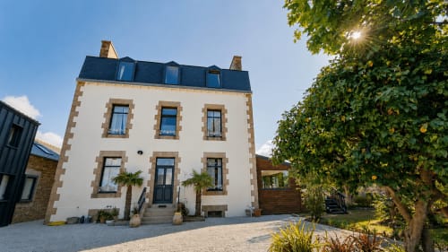 La Maison 1903, gîte de charme à Trévou-Tréguignec : façade en pierre blanche, toit mansardé et cour ornée de lierre