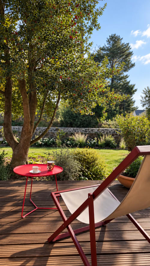 Chaise longue et table rouges face aux jardins de La Maison 1903, chambres d'hôtes à Trévou-Tréguignec en Bretagne