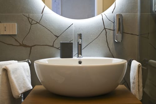 Modern bathroom sink in Levante apartment at Vimini Apulian Experience hotel, Bari with illuminated mirror and decorative