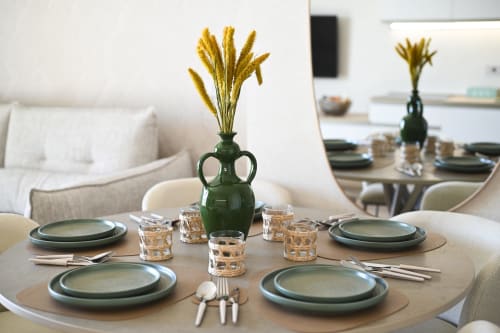 Elegant dining setup at Vimini Apulian Experience with green plates, golden dried flowers in vase, and sea view in Levante
