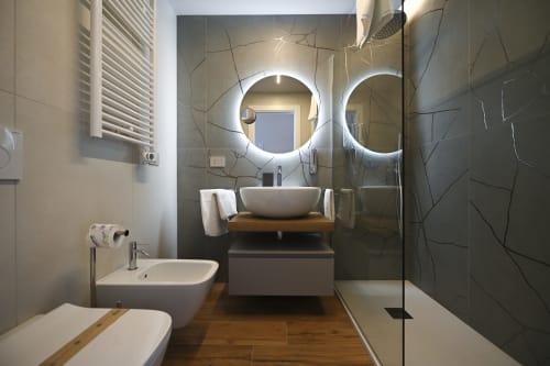 Modern bathroom in Levante apartment at Vimini Apulian Experience, Bari, with dual illuminated mirrors, vessel sink, and
