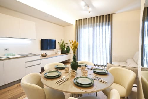 Modern apartment dining area at Vimini Apulian Experience with round table, cream chairs, open kitchen, and sea view in Bari