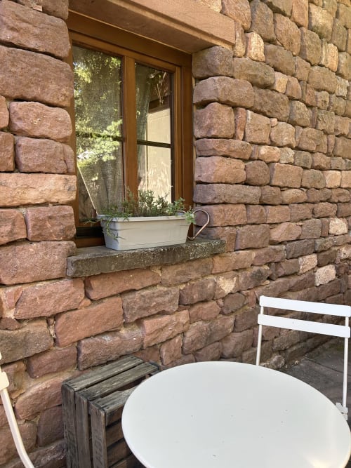 Fenêtre de chalet en pierre avec jardinière blanche aux Cabanes du Nideck, Oberhaslach, avec espace de détente extérieur et montagne
