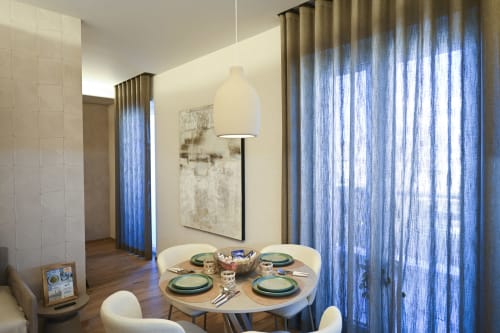 Ginestra apartment dining area at Vimini Apulian Experience with round table, blue curtains, pendant light, and garden views