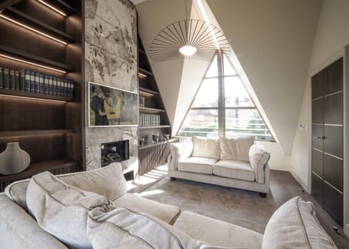 Luxury villa lounge at The Coach House, Oxford with cream sofas, triangular window, fireplace, and garden views