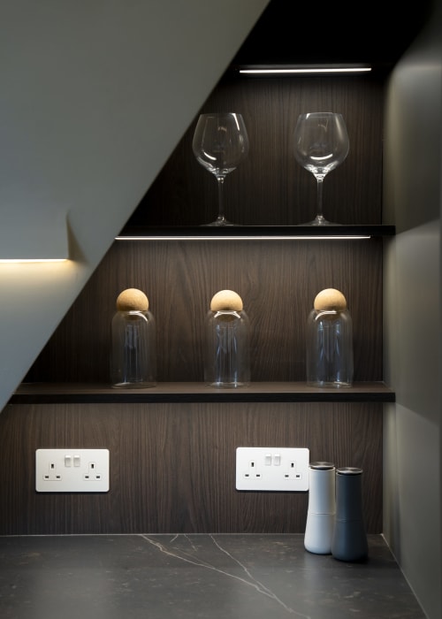 Modern wall shelving at The Coach House villa displaying wine glasses, glass containers with wooden lids, and amenities near