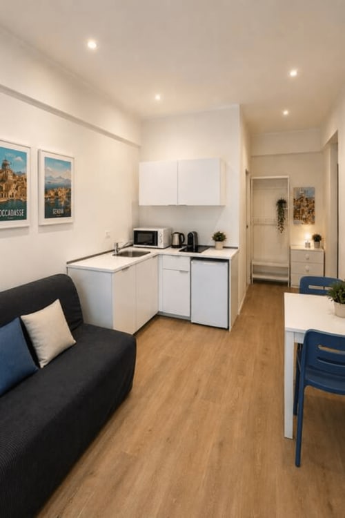 Moderno monolocale presso La Superba Stay Genova con angolo cottura, divano nero, zona pranzo e mobili bianchi