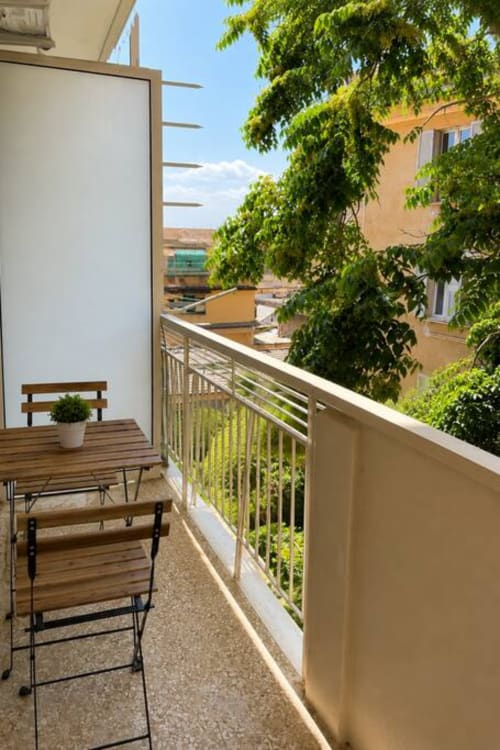 Balcone di La Superba Stay Genova con arredi in legno, rigogliose piante di edera e vista sulla città di Genova
