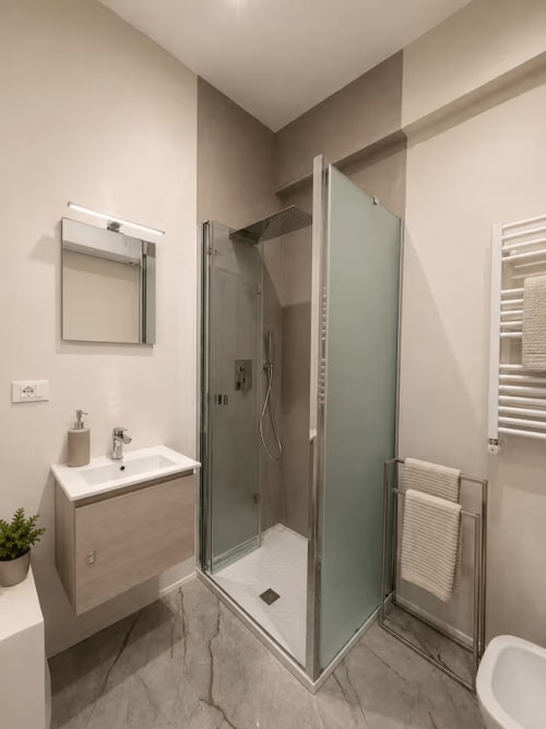 Bagno moderno nella Cittadella Suites di La Superba Stay Genova con doccia, lavabo, portasciugamani e arredamento neutro