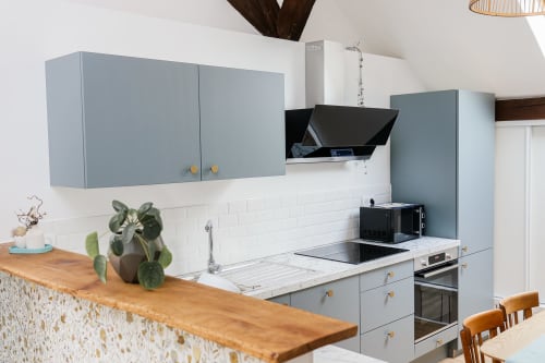Cuisine moderne aux Cabanes du Nideck : meubles gris, carrelage blanc, plan de travail bois, appareils inox