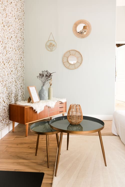 Intérieur de cottage moderne aux Cabanes du Nideck avec table basse ronde, commode vintage, miroirs tissés muraux, et