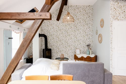Chambre douillette aux Cabanes du Nideck avec poutres apparentes, murs en terrazzo, mobilier bois et poêle noir
