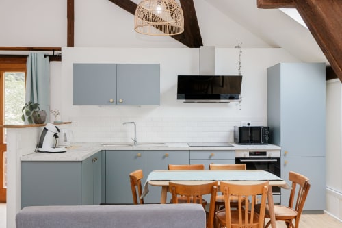Cuisine cottage moderne avec armoires bleues, carrelage métro blanc et chaises de salle à manger en bois aux Cabanes du Nideck, Alsace