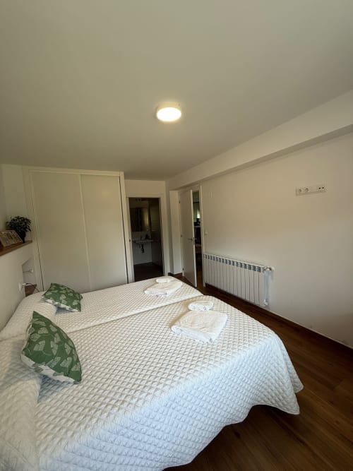 Habitación luminosa del hotel Bikarte Os Condes en Sober con cama doble, almohadas verdes, ropa de cama blanca y comodidades modernas