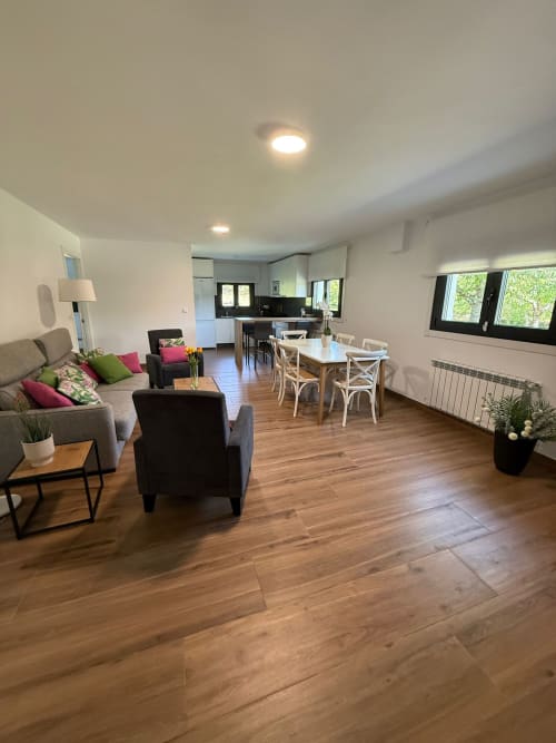 Habitación del hotel Bikarte Os Condes en Sober con sala de estar abierta, sofá, mesa de comedor y cocina moderna