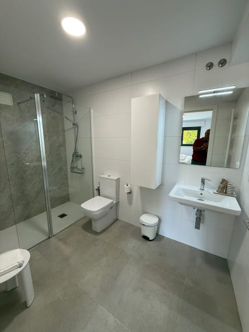 Baño moderno de la habitación Bikarte Hotel Os Condes en Sober con ducha a ras de suelo, azulejos blancos, lavamanos e inodoro