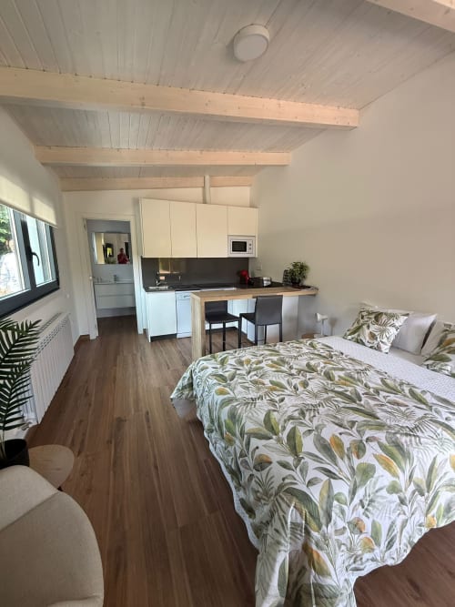 Habitación moderna en el hotel Bikarte de Sober con cama, cocineta, vigas vistas y piso de madera
