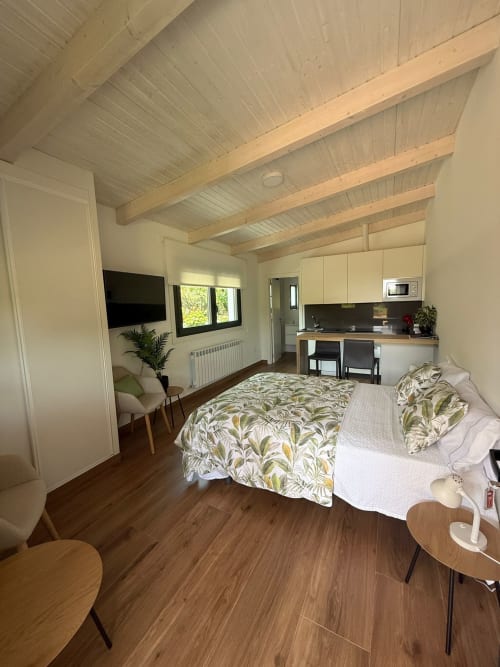 Habitación Adegas del hotel Bikarte en Sober con cama, cocineta, techo de vigas y suelos de madera