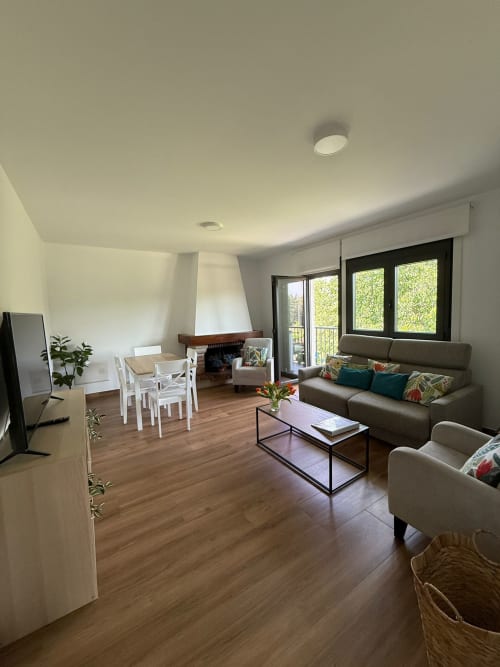 Habitación del hotel Bikarte Castiñeiros en Sober con sala de estar, sofá, comedor, chimenea y acceso a balcón