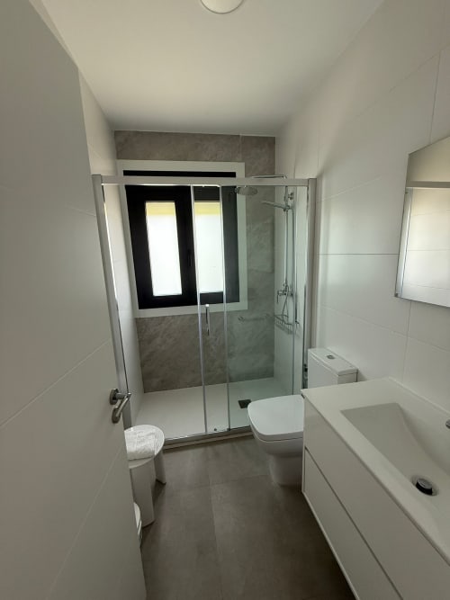 Baño moderno del hotel Bikarte en Sober con ducha de cristal, lavabo blanco, inodoro y suelo de azulejos
