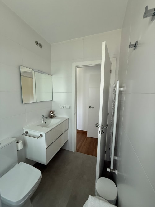 Baño moderno del hotel Bikarte en Sober con lavabo blanco, inodoro, ducha y toallero calefactable