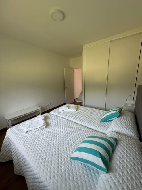 Luminosa habitación del hotel Bikarte en Sober con cama doble, almohadas de rayas turquesas, ropa blanca y armarios empotrados