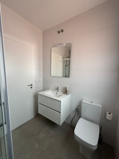 Baño moderno del hotel Bikarte en Sober con vanitory blanco, espejo, inodoro y paredes alicatadas