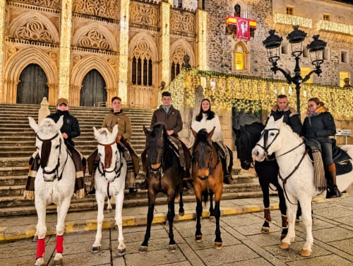 Seis huéspedes a caballo frente a la catedral iluminada de Guadalupe, Cáceres, España en El descanso del peregrino B&B
