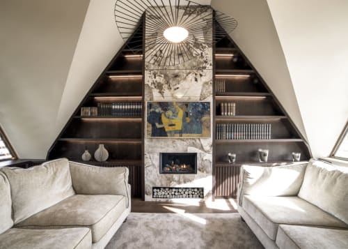 Luxury attic lounge at The Coach House with fireplace, built-in shelving, cream sofas and geometric ceiling light