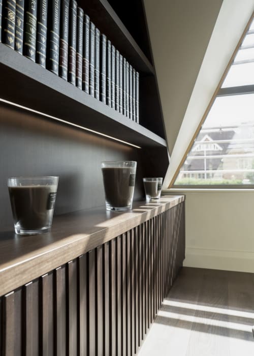 Modern hotel window seat at The Coach House with dark shelves of books, glasses of water, and countryside views