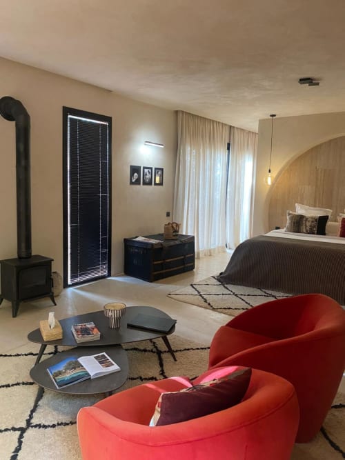 Suite contemporaine du riad Jardin Sakina à Marrakech avec lit king-size, fauteuils rouges, cheminée et patio privé
