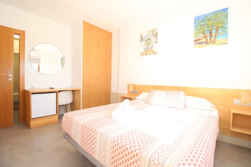 Habitación doble en Hostal Fornet Altea con muebles de madera, espejo redondo y vistas a las montañas de Altea, España
