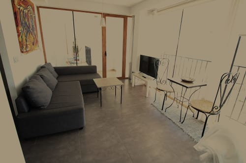 Amplia sala de estar en Hostal Fornet Altea con sofá gris, televisor, sillas de comedor y equipamiento moderno