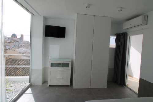 Habitación Suite Deluxe moderna con vistas al mar en Hostal Fornet Altea, España. Decoración minimalista blanca con TV, aire acondicionado y armario.