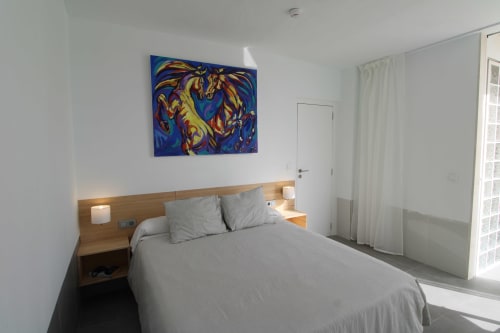 Habitación moderna en Hostal Fornet Altea con cama doble, cabecero de madera, arte abstracto colorido y acceso a balcón con vistas al mar