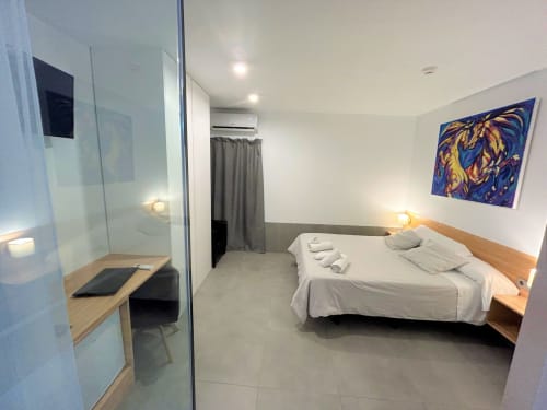 Dormitorio Modern Suite Deluxe del Hostal Fornet Altea con cama, baño privado, escritorio y arte contemporáneo