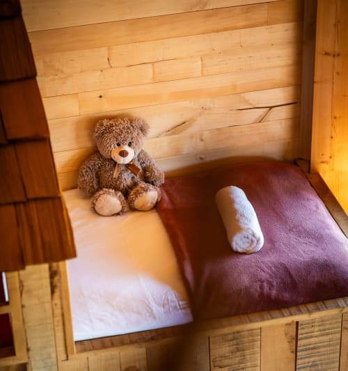 Gezellige houten slaapkamer in Domaine De Campagnac met knuffelbeer, opgewoven handdoek en bordeauxrood beddengoed