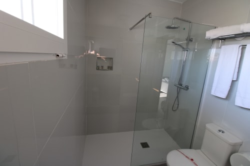 Baño moderno con cabina de ducha de cristal y accesorios blancos en Hostal Fornet Altea