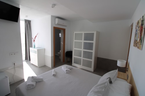 Moderna habitación Junior Suite en Hostal Fornet Altea con camas gemelas, armario blanco, TV y balcón con vistas al mar