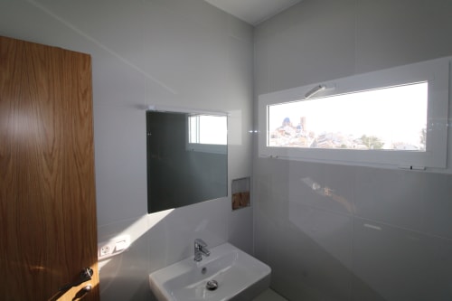 Baño moderno en Hostal Fornet Altea con ventana con vistas al mar y edificios costeros