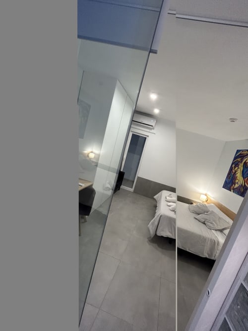 Habitación junior suite moderna en Hostal Fornet Altea con cama, mamparas de cristal y mobiliario contemporáneo
