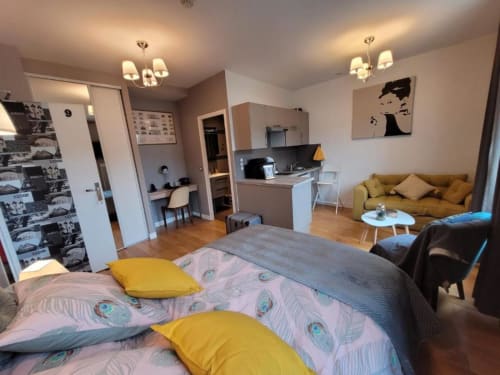 Deluxe apartment at Hôtel OH Sèvres with bed, mustard sofa, kitchenette, and modern décor