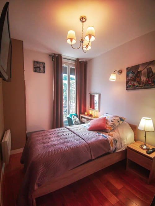 Chambre Angelina à l'Hôtel OH Sèvres Autrement avec vue sur la ville, murs roses, lit en bois et éclairage chaleureux